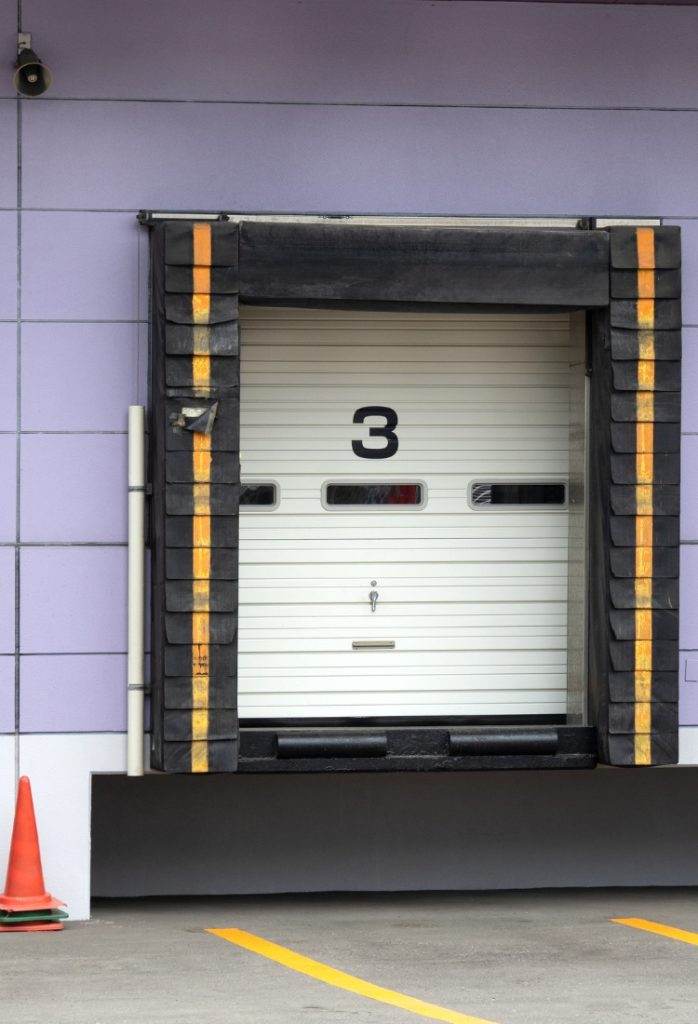 Warehouse loading dock door number three with safety markings in an urban area Warehouse loading dock door number three with safety markings in an urban area