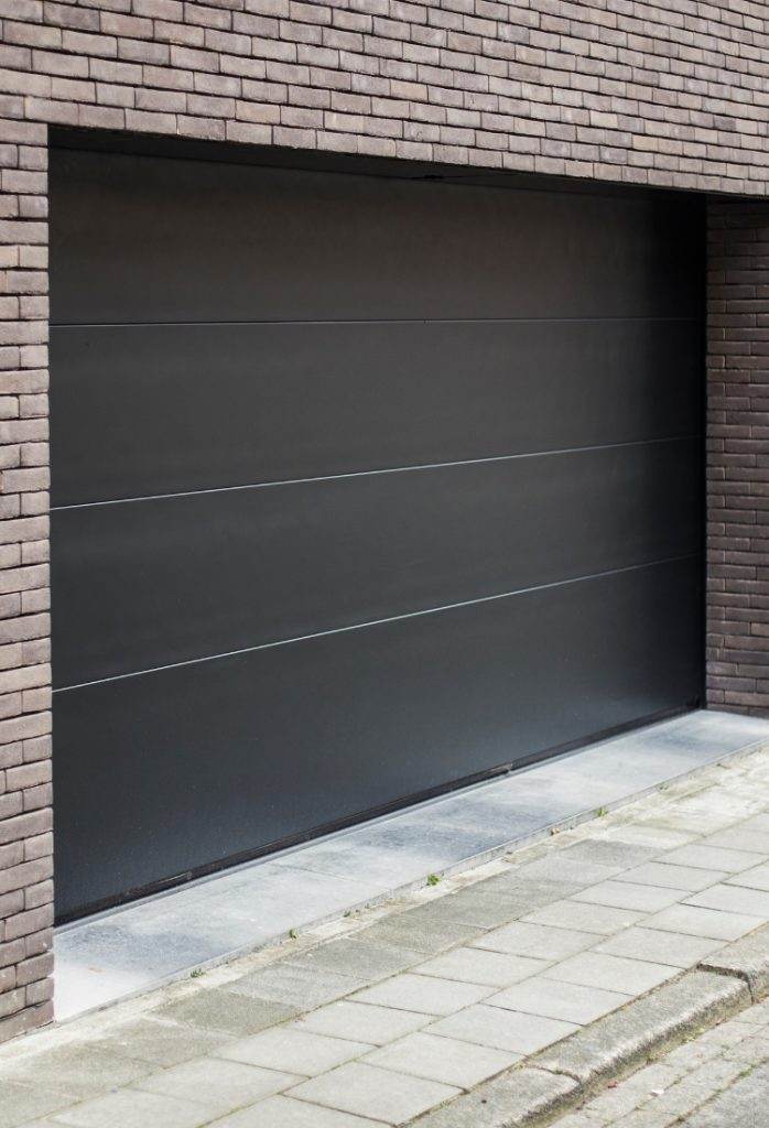 Modern garage door design integrated into brick building facade in urban neighborhood despite overcast sky Modern garage door design integrated into brick building facade in urban neighborhood despite overcast sky