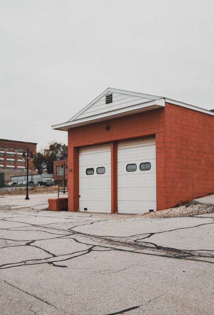 Bright orange building with garage doors standing on a quiet street in an urban area during overcast weather Bright orange building with garage doors standing on a quiet street in an urban area during overcast weather