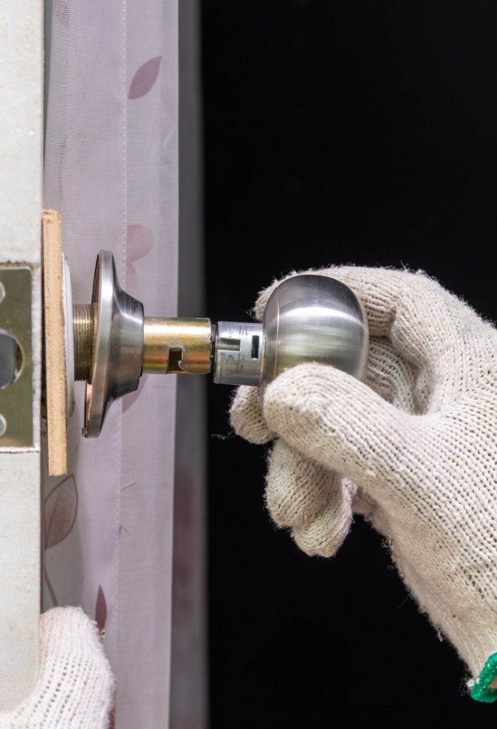 Hand inserting a doorknob into a door in a home renovation project in the late afternoon Hand inserting a doorknob into a door in a home renovation project in the late afternoon