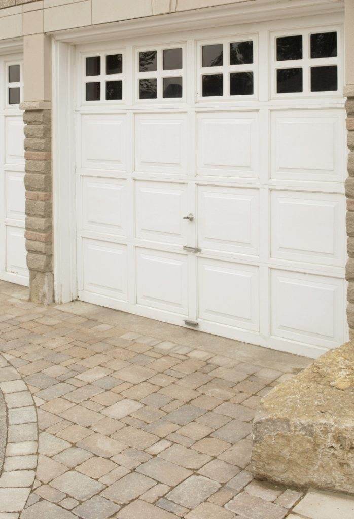 Elegant white garage door with stone accents and paved driveway in a modern residential setting Elegant white garage door with stone accents and paved driveway in a modern residential setting