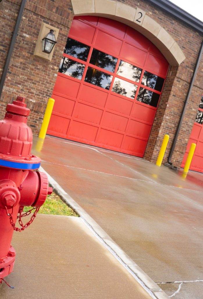 Fire hydrant in front of fire station with bright red doors on a rainy day Fire hydrant in front of fire station with bright red doors on a rainy day
