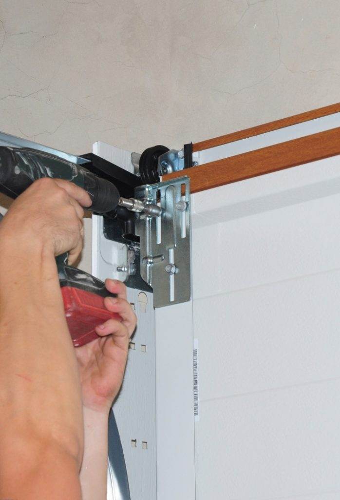 Installing a garage door track with a cordless drill in a residential garage during daylight hours Installing a garage door track with a cordless drill in a residential garage during daylight hours