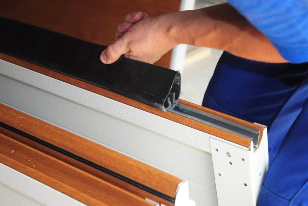 Person installing a seal strip on a sliding door track in a home improvement project Person installing a seal strip on a sliding door track in a home improvement project