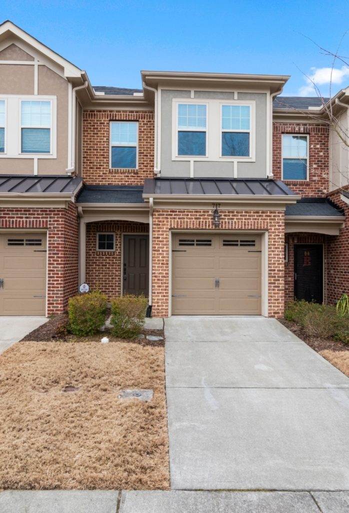 Townhouse exterior with modern architecture and subtle landscaping in a suburban neighborhood during daylight Townhouse exterior with modern architecture and subtle landscaping in a suburban neighborhood during daylight