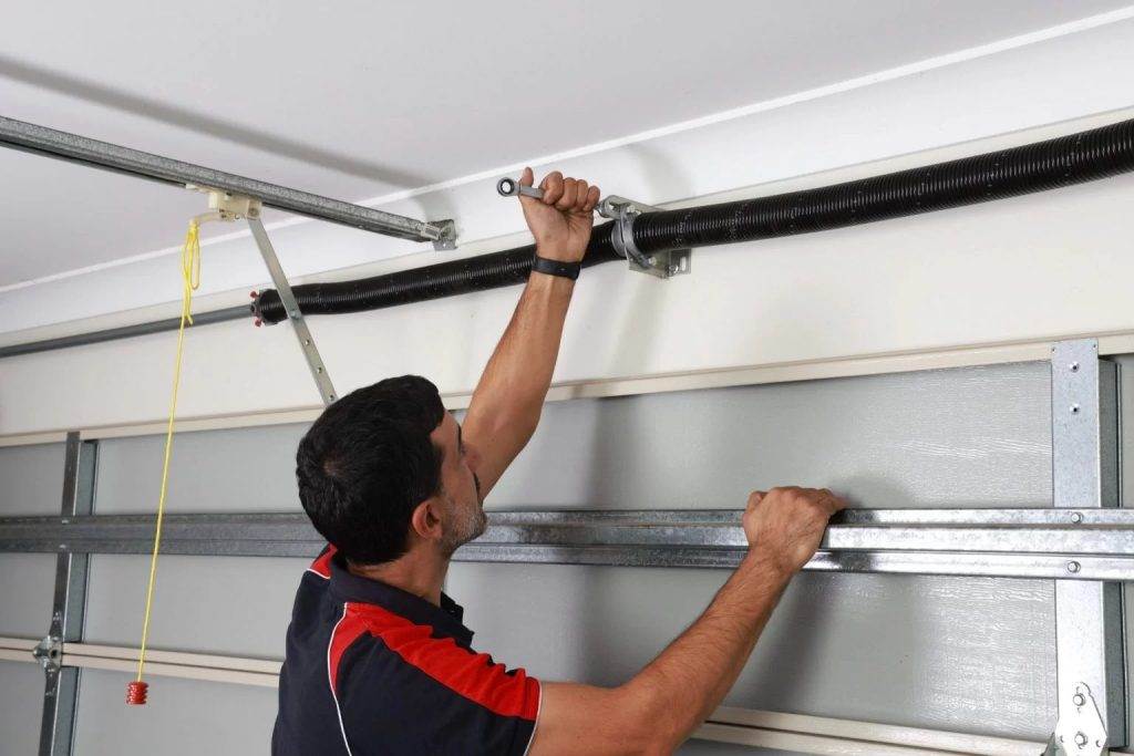 Technician repairs garage door mechanism using a wrench in a residential home setting Technician repairs garage door mechanism using a wrench in a residential home setting