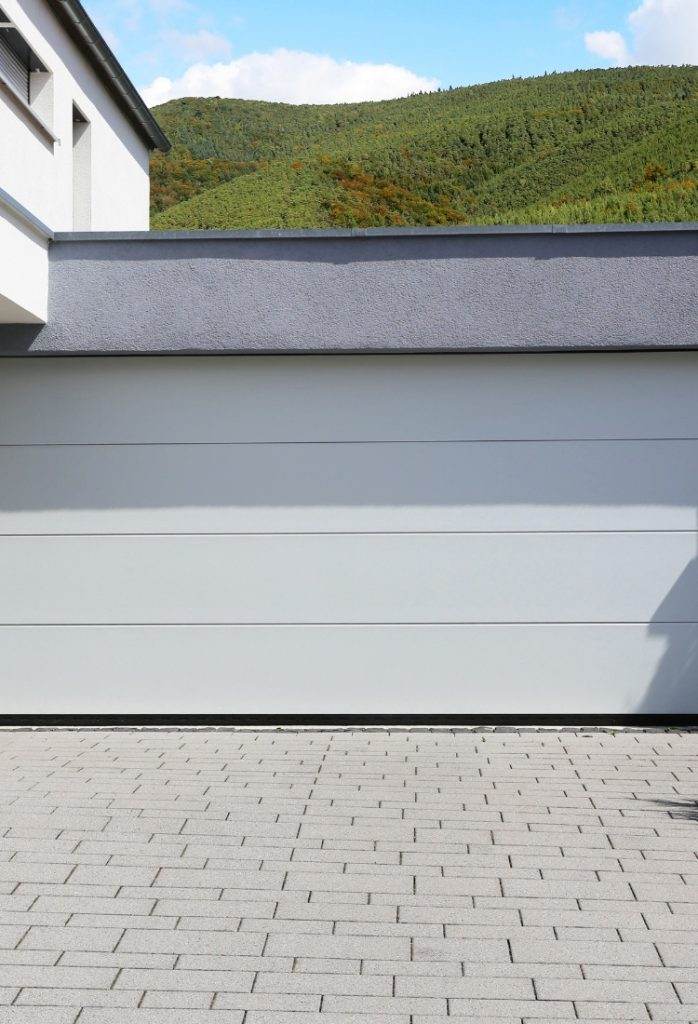 Modern garage design with smooth grey surface and green hillside in the background on a sunny day Modern garage design with smooth grey surface and green hillside in the background on a sunny day
