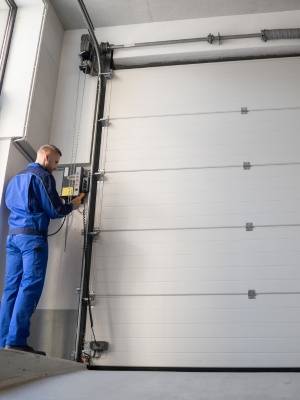 Custom garage door technician adjusting controls while working on design in modern garage